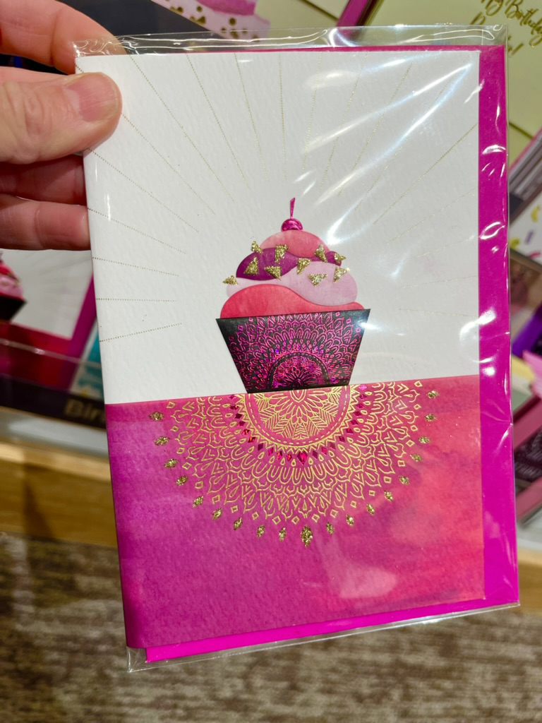 Licensed greeting card with cupcake design held in a retail store